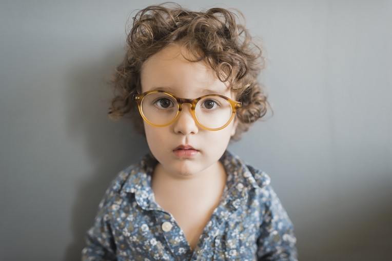 Young pediatric patient wearing round prescription glasses.
